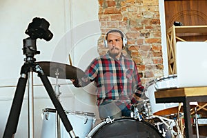 Caucasian musician playing drumms during online concert with the band at home isolated and quarantined, inspired