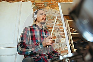 Caucasian musician playing drumms during online concert with the band at home isolated and quarantined, inspired