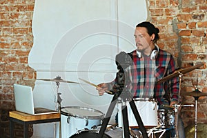 Caucasian musician playing drumms during online concert with the band at home isolated and quarantined, inspired