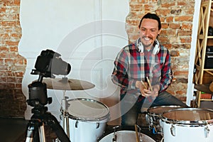 Caucasian musician playing drumms during online concert with the band at home isolated and quarantined, smiling