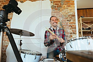 Caucasian musician playing drumms during online concert with the band at home  and quarantined, greeting