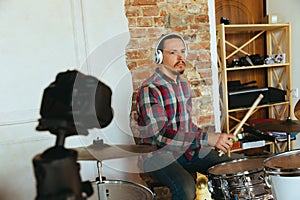 Caucasian musician playing drumms during online concert with the band at home  and quarantined, inspired