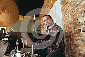 Caucasian musician playing drumms during online concert with the band at home  and quarantined, inspired