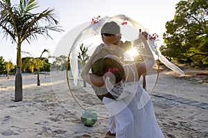Caucasian newlywed couple dancing romantically at wedding ceremony at beach during sunset