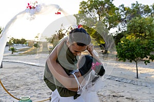 Caucasian newlywed couple dancing at wedding ceremony at beach during sunset