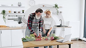 Caucasian old married man and wife prepare healthy salad.