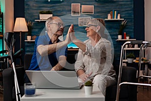 Caucasian old people highfive while sitting on sofa