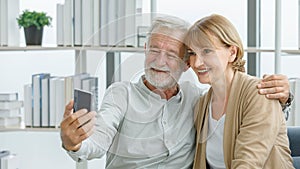 Caucasian old senior elderly happy lovely married couple grandparent grey bearded husband and pretty wife sitting on sofa smiling