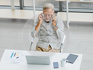 Caucasian old senior stress upset male businessman entrepreneur sitting at working desk having headache after reading graph chart
