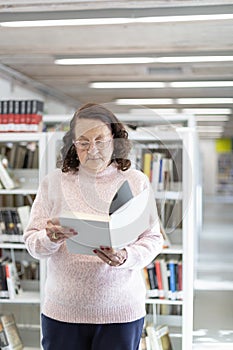 Caucasian older woman reading a book in a public library
