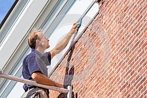 Caucasian painter cleans roof molding with cloth