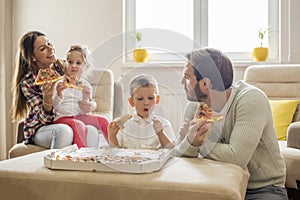 Caucasian parents eating pizza with their children at home