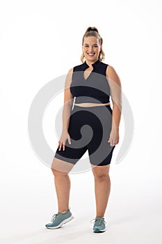 Caucasian plus size female model with hands on hips on white background