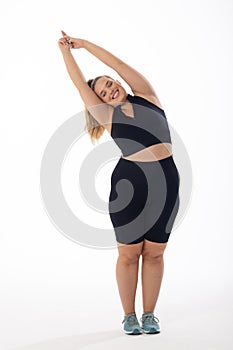 Caucasian plus-size model, long blonde hair, stretches arms up on white background