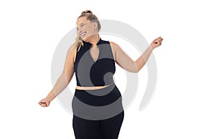 Caucasian plus-size woman in black activewear dances on white background
