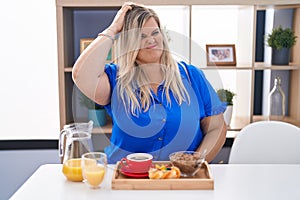 Caucasian plus size woman eating breakfast at home confuse and wonder about question