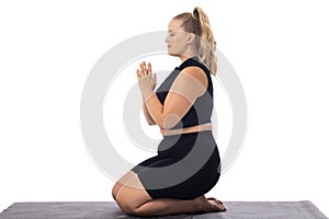 Caucasian plus-size young woman in black does yoga on a white background, copy space