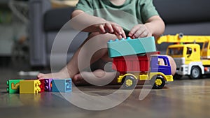 caucasian preschooler boy kid child playing toy car truck plastic bricks floor