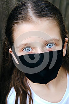 Caucasian preteen girl in a cloth dust mask outside. Close up portrait