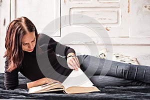 Caucasian pretty brunette woman laying and reading a book indoor