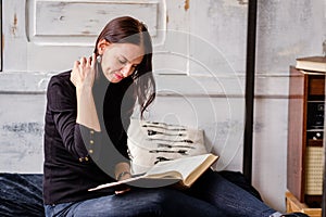 Caucasian pretty brunette woman sitting and reading a book indoo