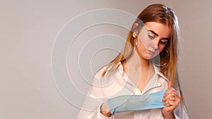 Caucasian pretty female with piercing in nose removes blue glove from her hand