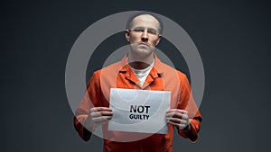 Caucasian prisoner holding Not guilty sign, asking for justice, human rights