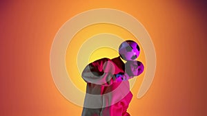 Caucasian professional soccer player practicing with football ball juggling on head, neon light. Studio shoot of