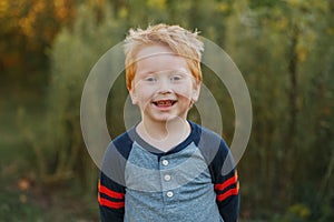 Caucasian red-haired cute handsome preschool boy. Adorable child standing outside on autumn fall day.