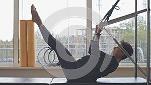 Caucasian retiree doing leg scissors exercise and lying down on bench. Wide shot side view of confident Caucasian senior