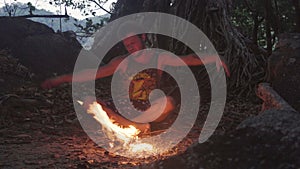 Caucasian Savage Man Burning Little Campfire in the Tropical Forest at Twilight to Boil Kettle with Rice for Dinner