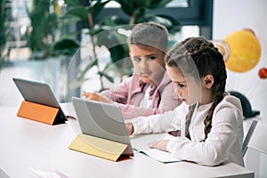 Caucasian schoolkids using digital tablets while studying together in class