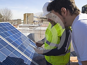 Caucasian seasoned technician showing the app to his young client beside the solar panels