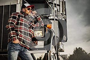 Caucasian Semi Truck Driver Relaxing Next to His Truck