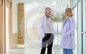 Caucasian senior beard male and female doctors wearing white gown uniforms with stethoscope, consulting, talking to each other in