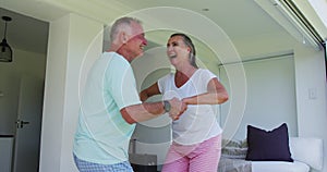 Caucasian senior couple dancing together at home