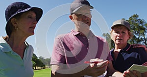 Caucasian senior couple discussing and writing golf score on scorecard at golf course