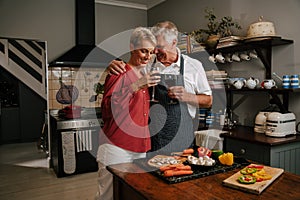 Caucasian senior couple drinking wine in kitchen cooking dinner