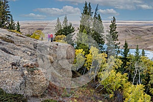 A caucasian senior couple looking out over fall colours from the Conglomerate Cliffs in Cypress Hills, SK