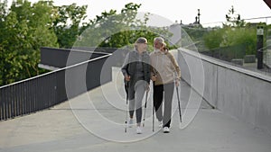 Caucasian senior couple nordic walking in the park and talking to each other. Aging youthfully. Active leisure. Elderly