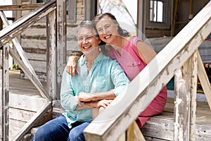 Caucasian senior couple smiling cheerfully and sitting on staircase outside cottage