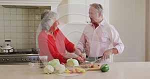 Caucasian senior couple smiling while looking at each other in the kitchen at home