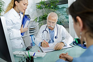 caucasian senior doctor in office with assistant