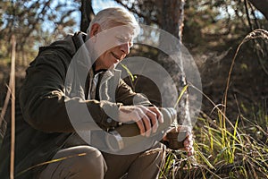 Caucasian senior man pouring hot beverage to mug from the thermos