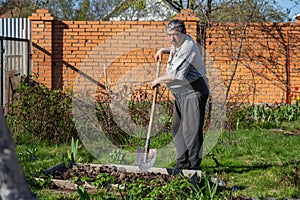 Caucasian Senior man with shovel digging garden bed or farm