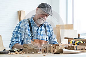 Caucasian senior old white bearded man carpenter in apron, hat working in workshop, use pencil sketching a design on paper,