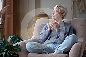 Caucasian senior woman relaxing drinking cup of tea in armchair at home