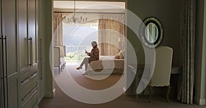 Caucasian senior woman using smartphone while sitting on the bed at home