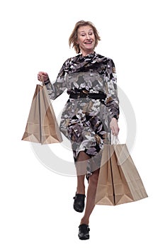 Caucasian senior woman walking with shopping bags smiling at viewer