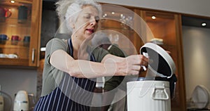 Caucasian senior woman wearing apron putting all the waste in the dustbin in the kitchen at home